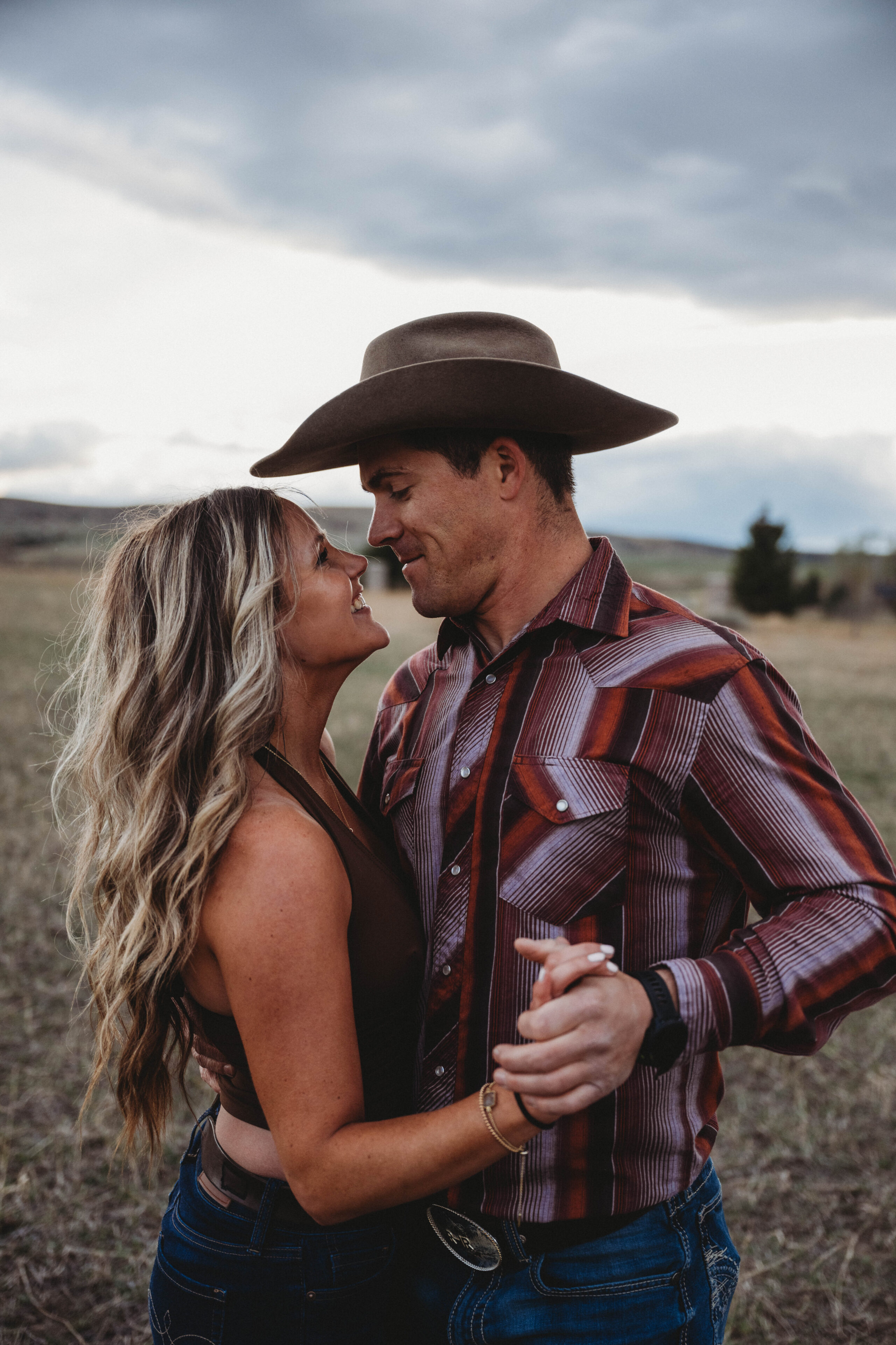 Couple embracing in Bozeman Montana during a romantic couples photography session with western style outfits