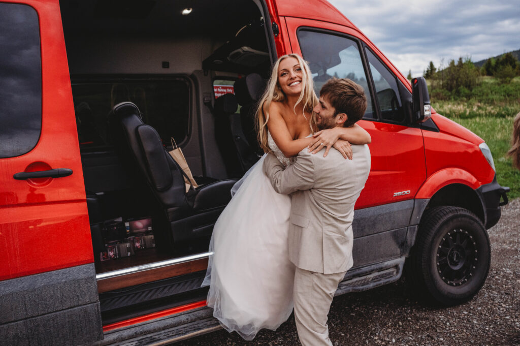 groom helping bride down from the bus for pictures